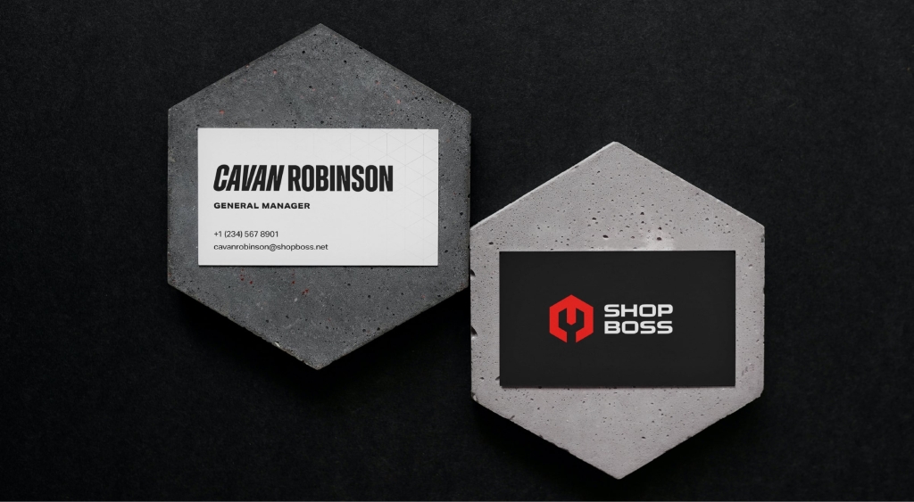 Two Shop Boss business cards set atop concrete hexagons.